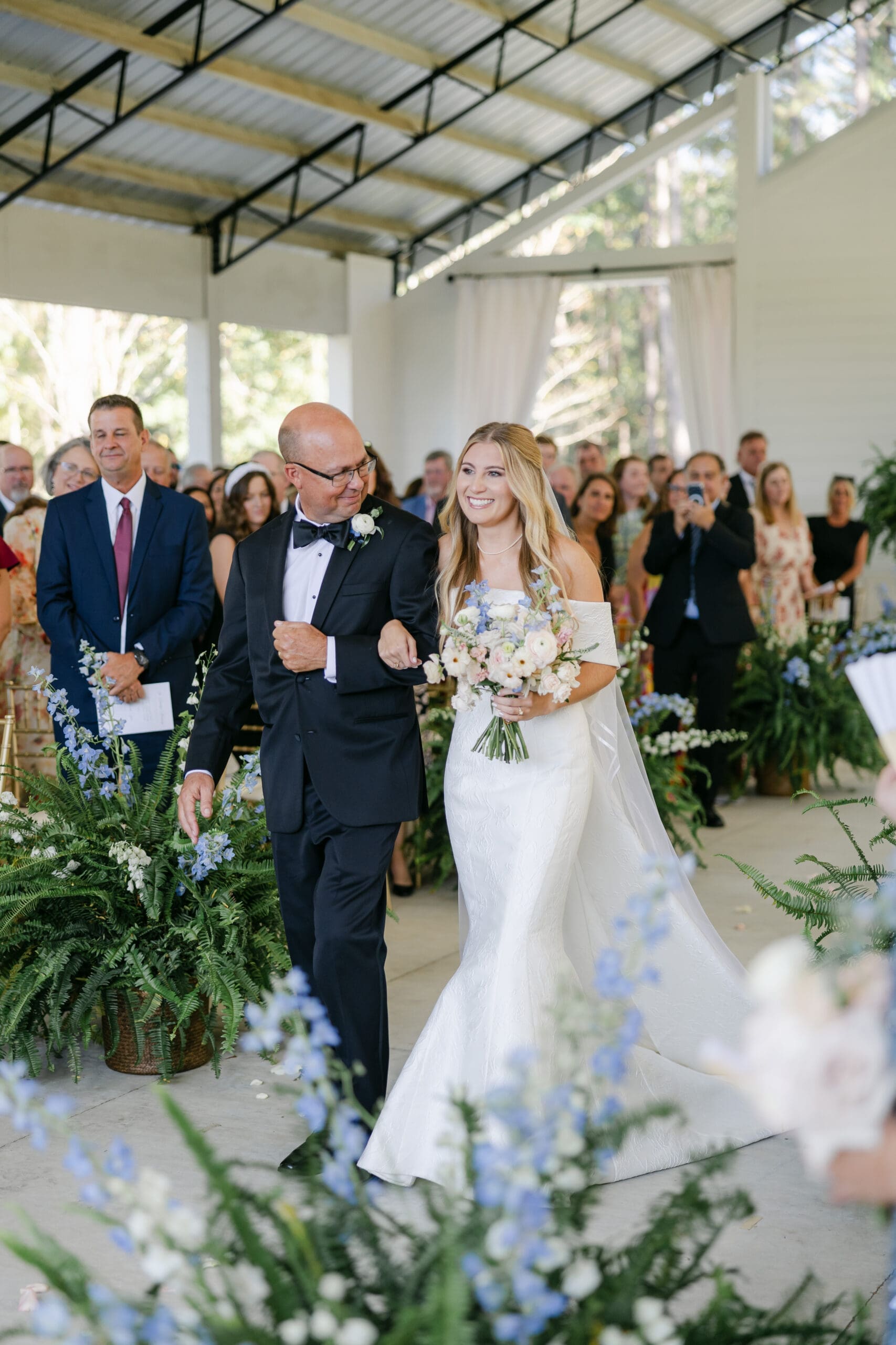 A bride and her dad walking down the aisle and her dad is looking at her