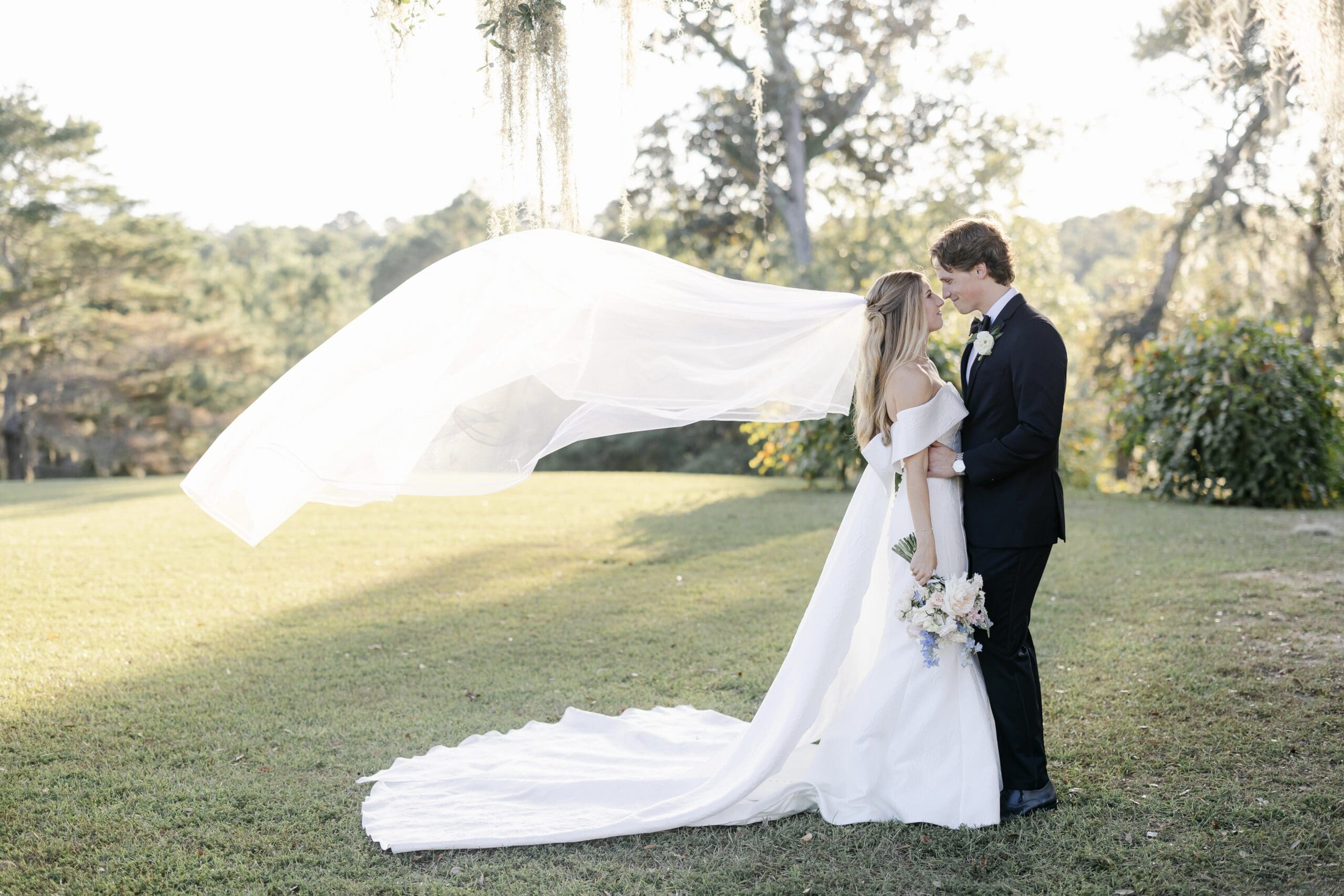 A veil flying in the wind while a couple takes sunset and golden hour portraits